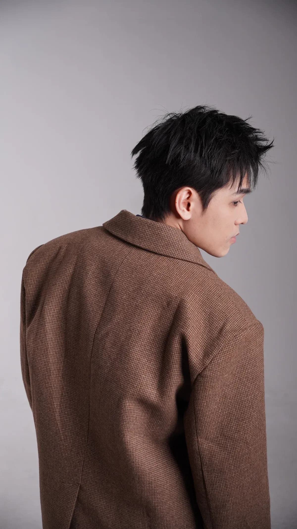 Kien Pham looking over his shoulder in a brown jacket