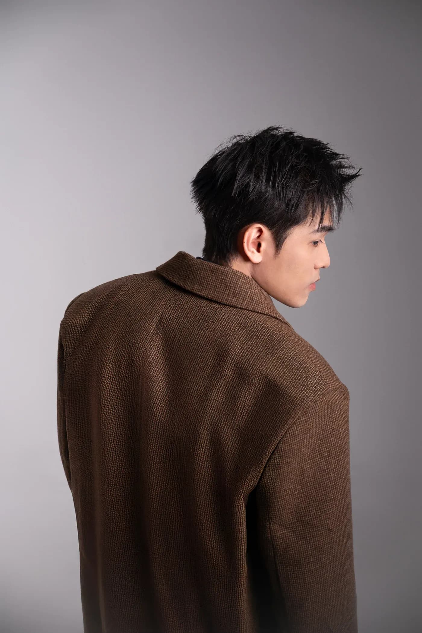 Kien Pham looking over his shoulder in a brown jacket
